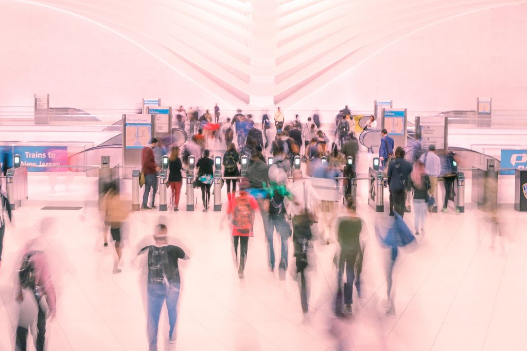 A crow of people walking to check-in screens at a train station. 