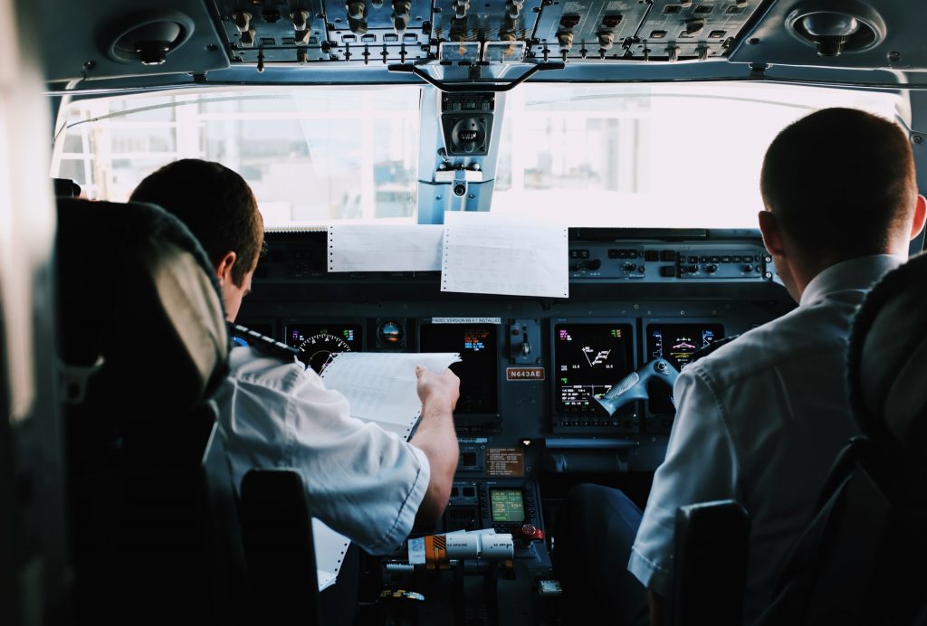 A backview of two pilots sitting in the cockpit and filling out pre-flight documentation.