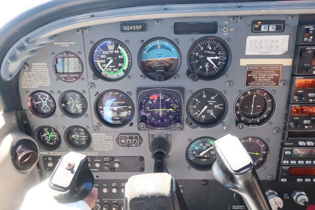 An airplane instrument panel and a control column in a cockpit.