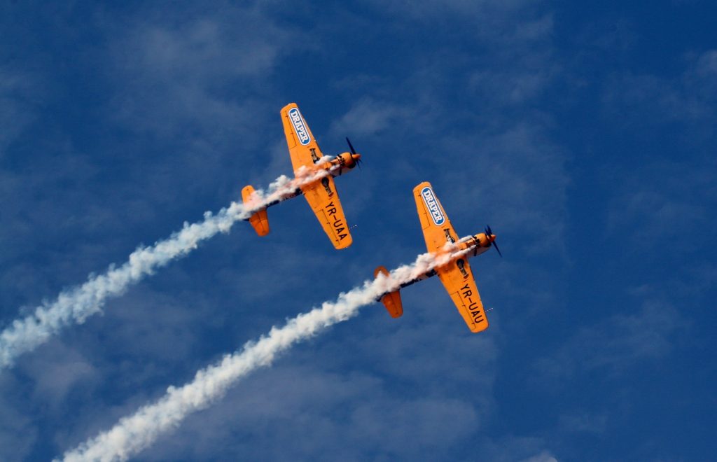 Two stunt airplanes performing a maneuver in a clear blue sky. 