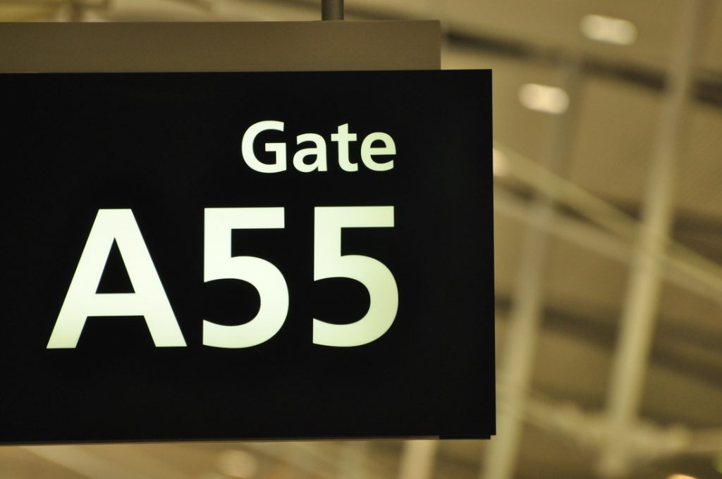 A sign hanging at the airport pointing to gate A55.