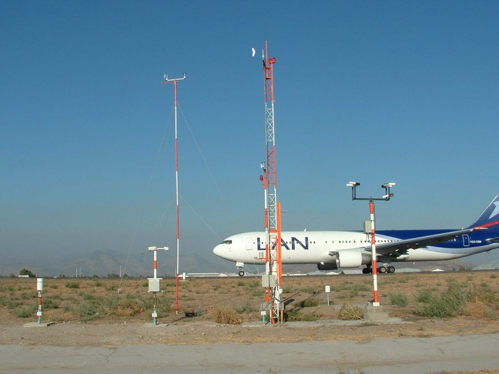 Automated weather observing system (AWOS) next to a runway with a landed aircraft. 