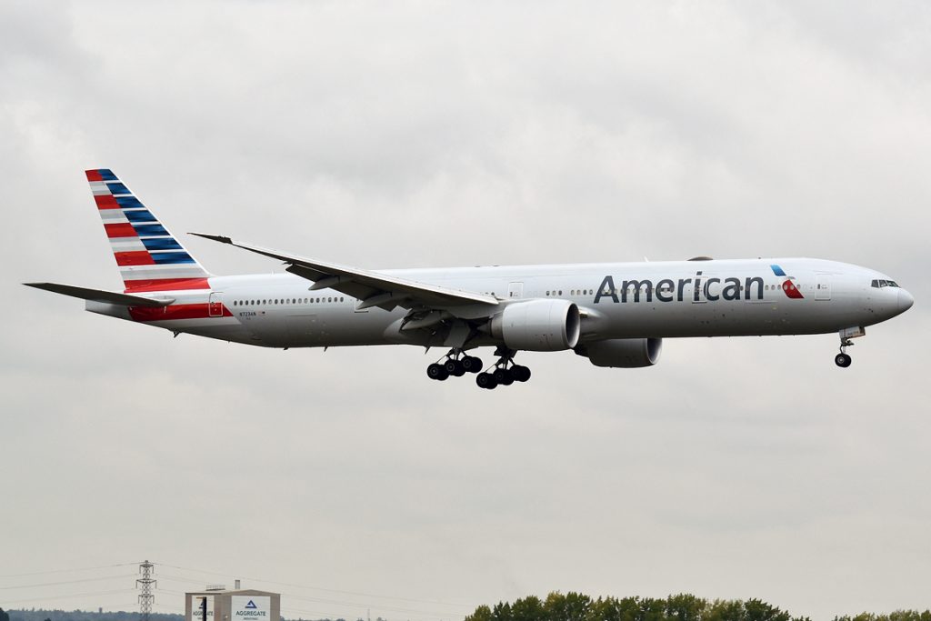 An American Airlines airliner Boeing 777-323 landing at an airport on a cloudy day.