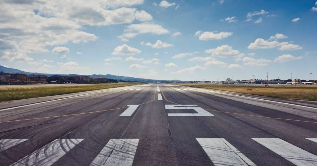 A central view of a runway with a marking '15' at Rome Ciampino airport on a clear day in Italy.
