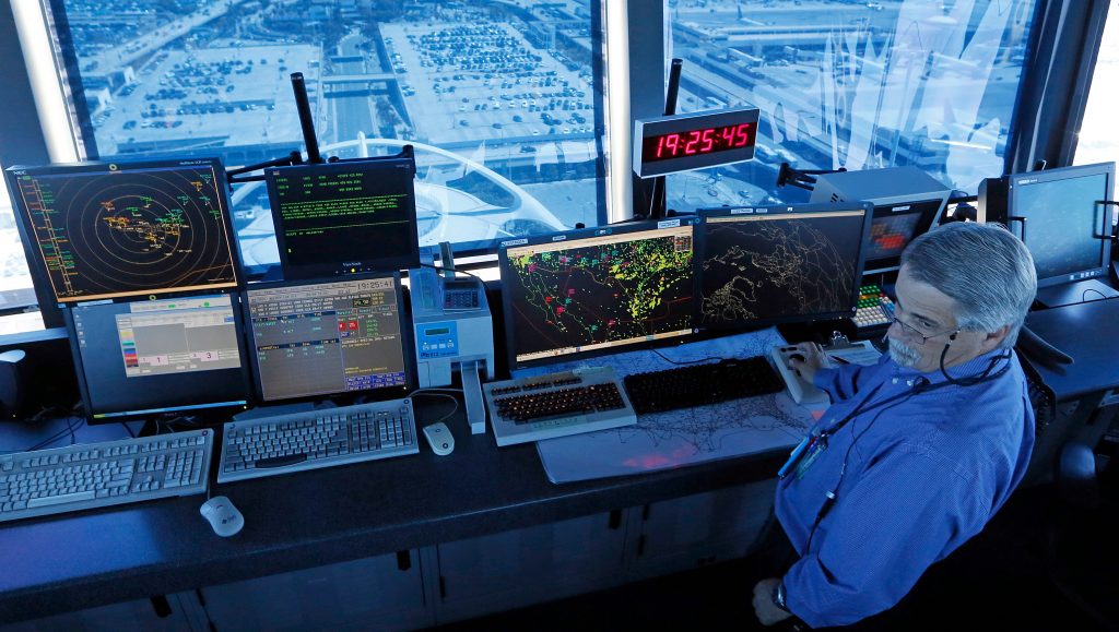 A view from an air traffic control tower and air traffic controller's panel of screens.