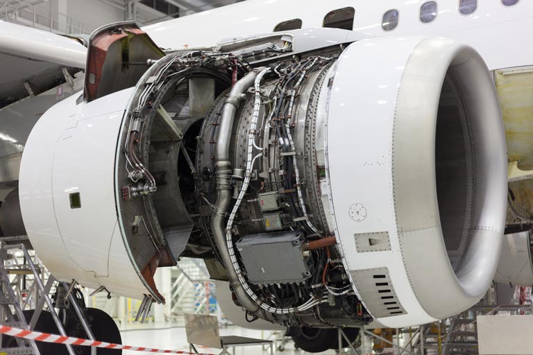 A jet engine of an aircraft without its covers, exposing an intricate hydraulic system.