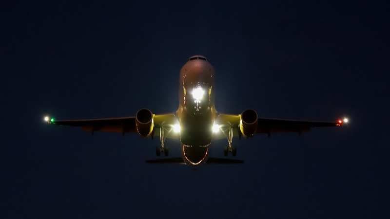 A passenger aircraft with landing lights on is landing at an airport.