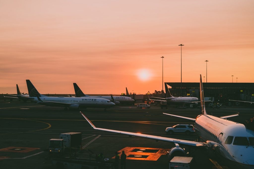 United Airlines aircrafts parked by a taxiway at an airport at sunrise.