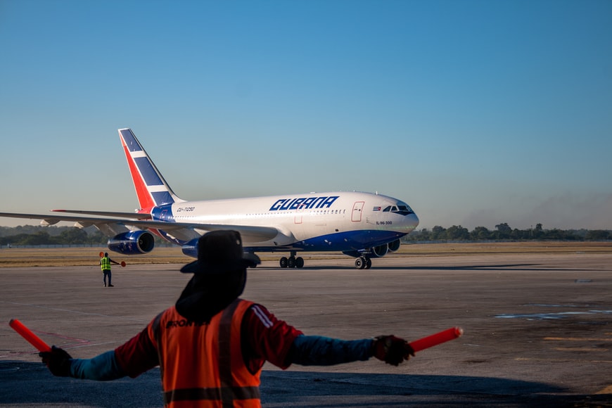 A landing aircraft and ground support staff marshalling the airplane. 