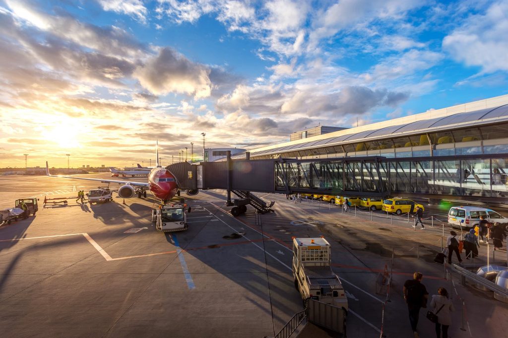 An operational airport terminal with a central view of an aircraft attached to a jet bridge in Copenhagen airport. 