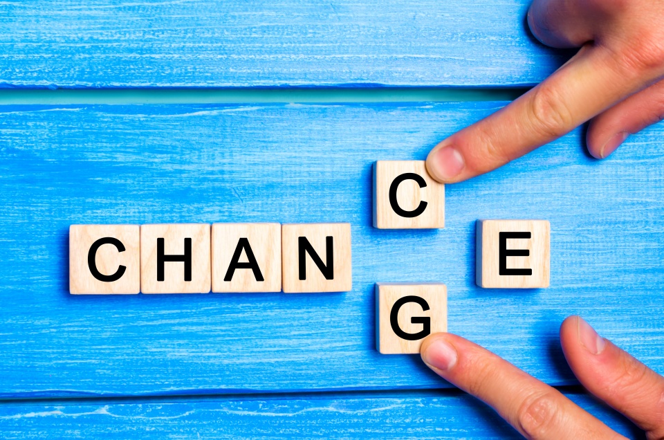 Wooden blocks which spell "change" and "chance" on a blue wooden surface.