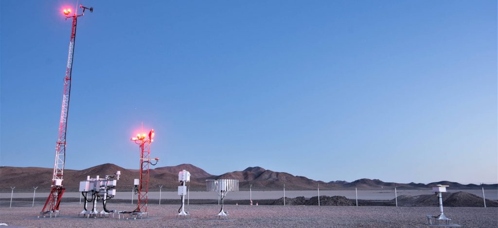 AWOS III or automated weather observing system stationed in a field surrounded by hills.