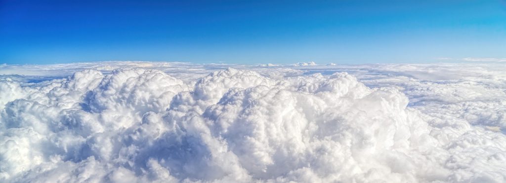 A panoramic view of clouds and a blue sky from a high altitude.