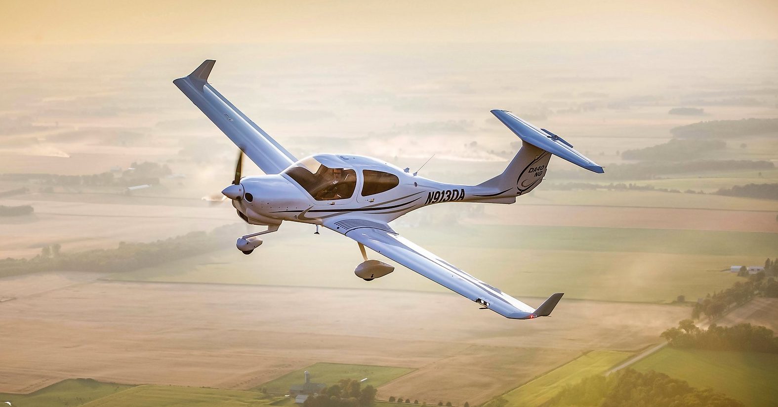 Diamond DA40 series aircraft flying high over the countryside. 