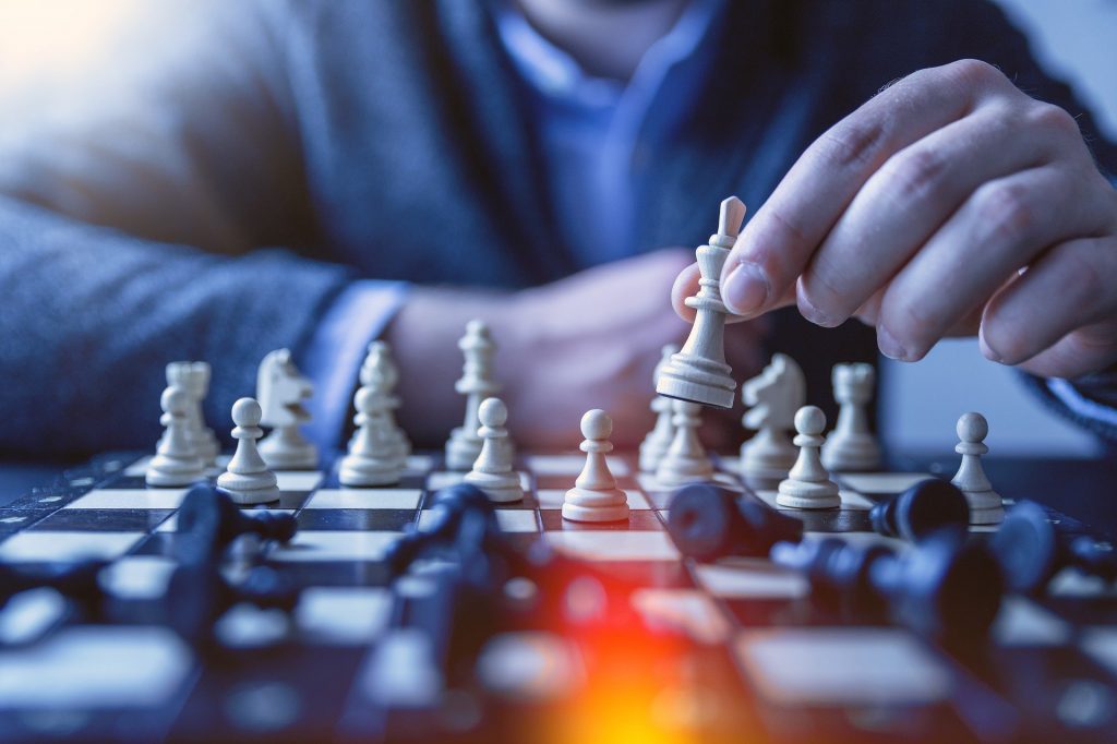 A depiction of developing and executing change plans: a man in suit playing chess as white pieces.