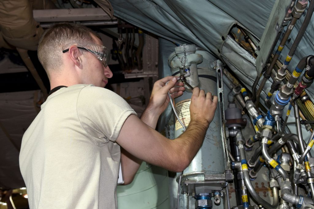 Airman Logan Wilson, of Plant City, Florida, works on a utility hydraulics system reservoir on a C-130 trainer 