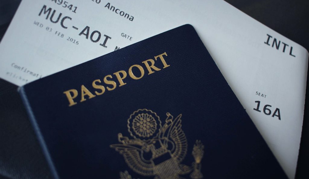 A country's passport in blue and a boarding pass for a flight. 