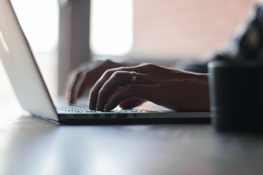 A person taking part in online training course and typing on his laptop keyboard.