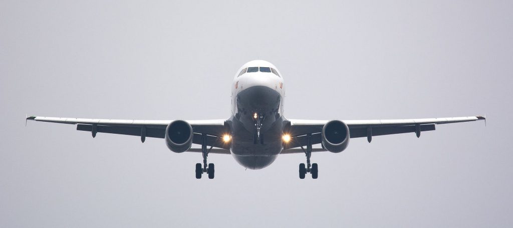 A central view of a passenger aircraft about to land at an airport on a gray cloudy day. 