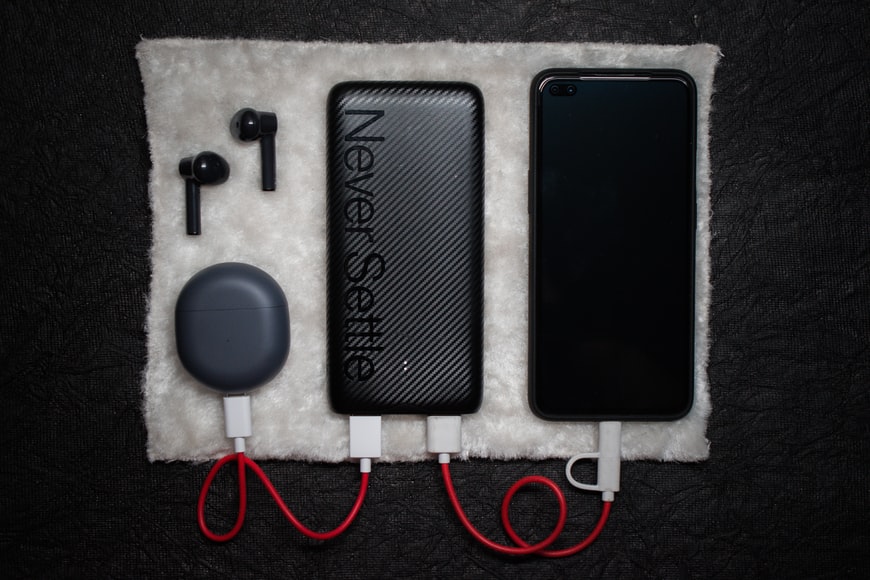 A black power bank charging a earphone case and a smartphone.