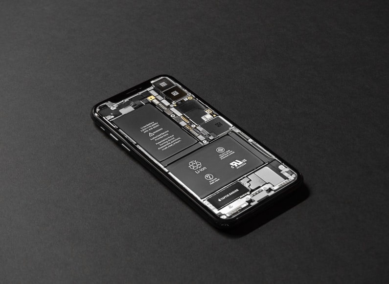 An iPhone without its case on the back, showing the battery and other parts of the device.