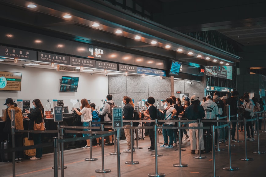 A crowd of people standing at a train ticket sales point at a train station in Taiwan.