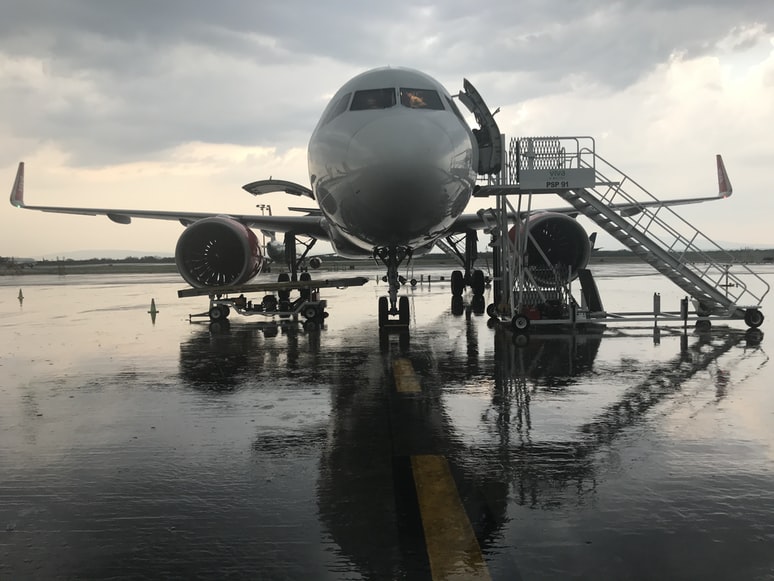 A white airliner with a boarding platform stationed at an airport, ready for boarding. 