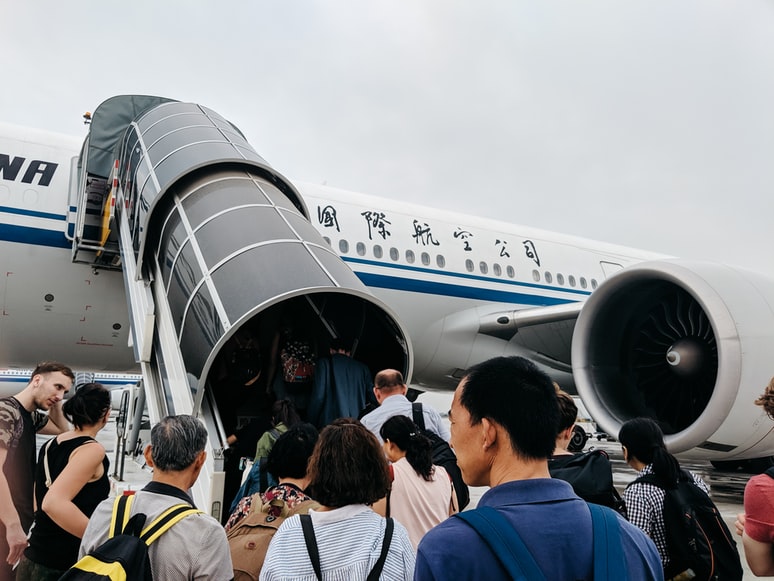 Many passengers boarding an Air China aircraft on a cloudy day.