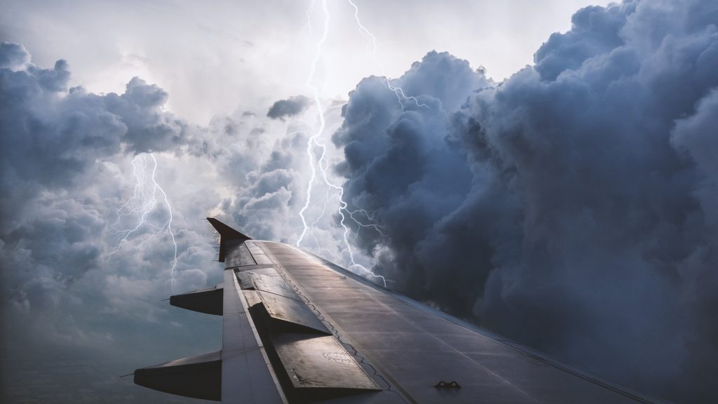 A render of an aircraft flying through a thunderstorm with lightning.