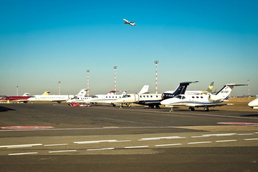 Small private jets parked on an apron at an airport on a clear day. 