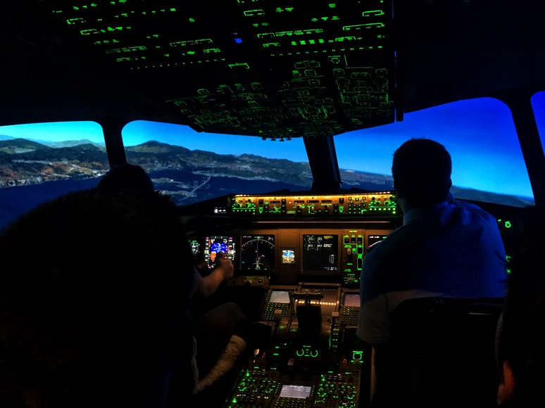 A flight instructor and a young student sitting in a flight simulator cockpit and trying to become a pilot.