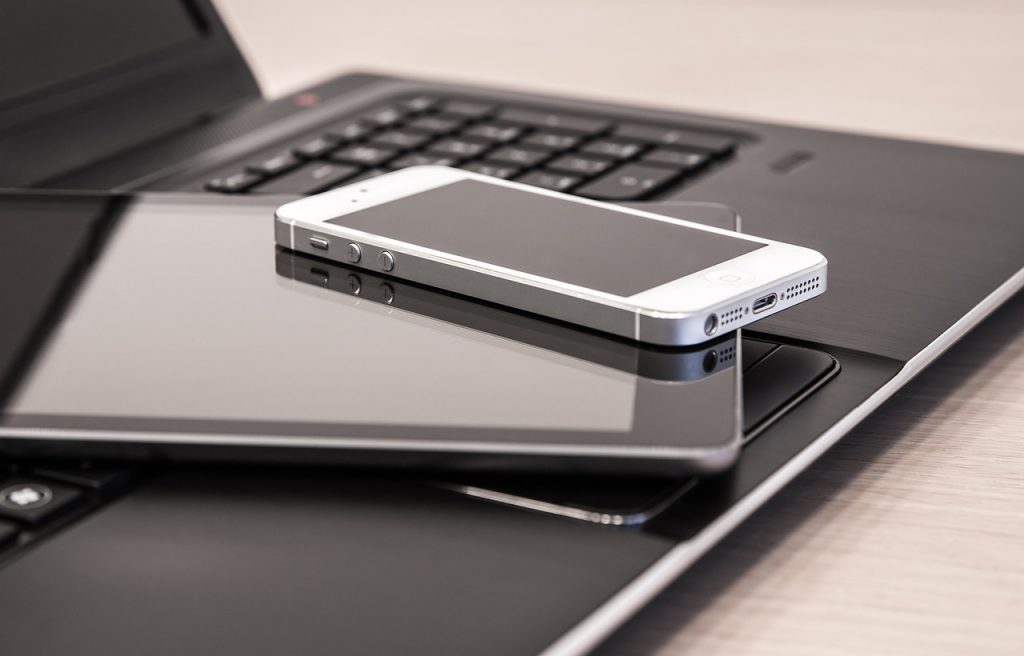 Lithium-ion battery-equipped electronic devices on a table: a laptop computer, a smartphone, and a tablet.