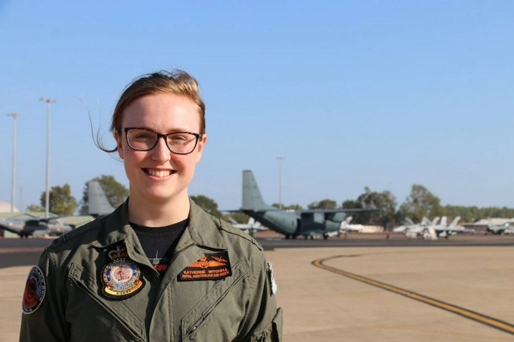 A military pilot wearing corrective glasses standing on a military airfield taxiway.