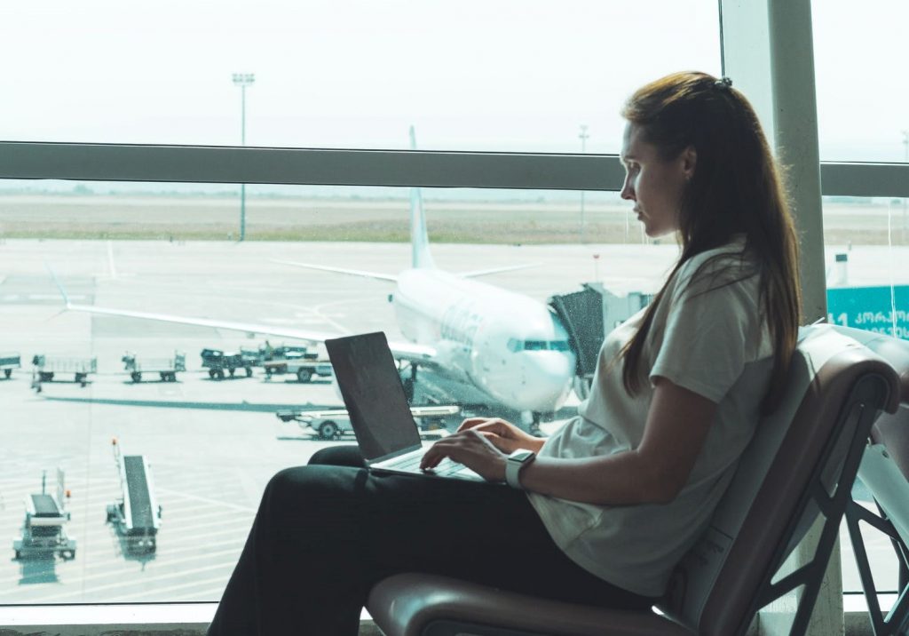A woman using her laptop to participate in an online training course at an airport.