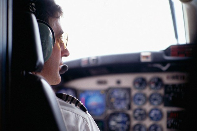 Pilot with glasses is looking through window