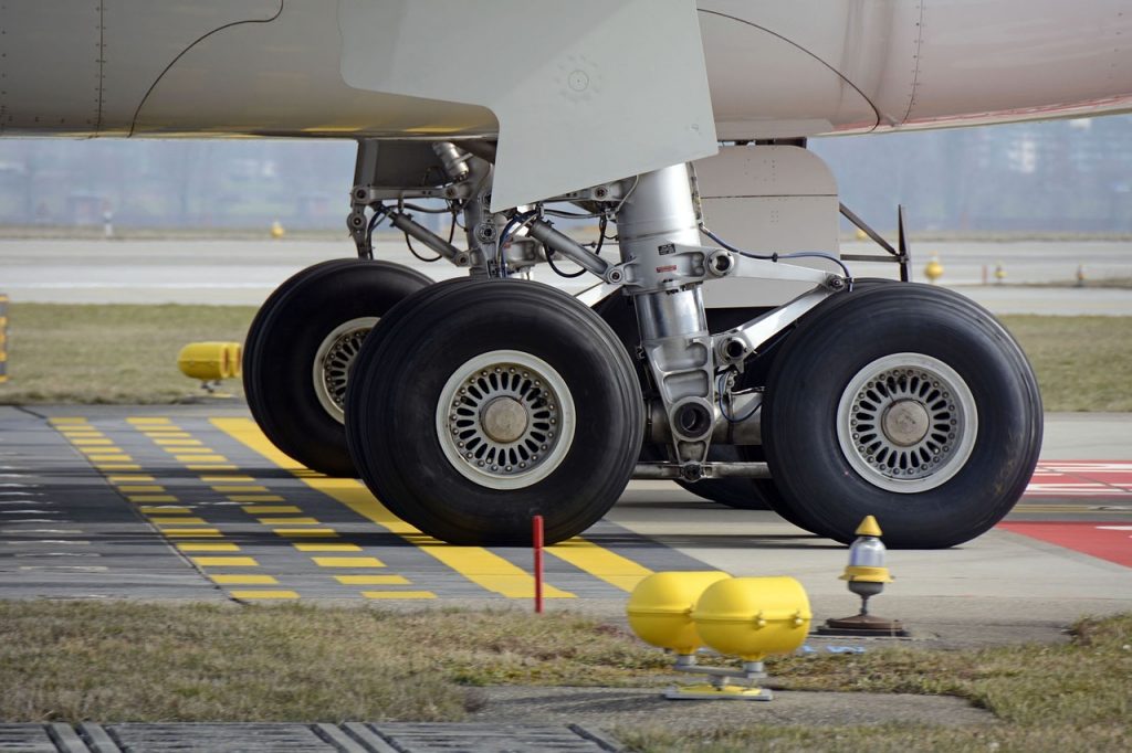 A view of a main landing gear, aircraft tires and wheels of an aircraft on a runway. 