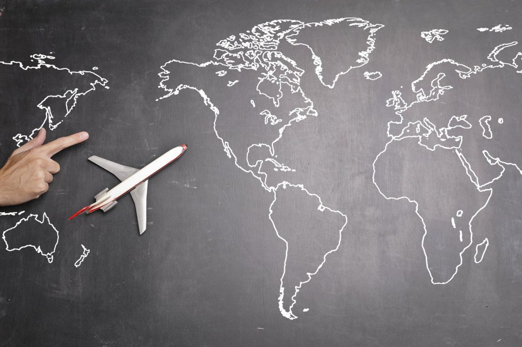 A visualization for international travels and travel for work: an airplane on a gray world map with a hand pointing at an eastern direction.