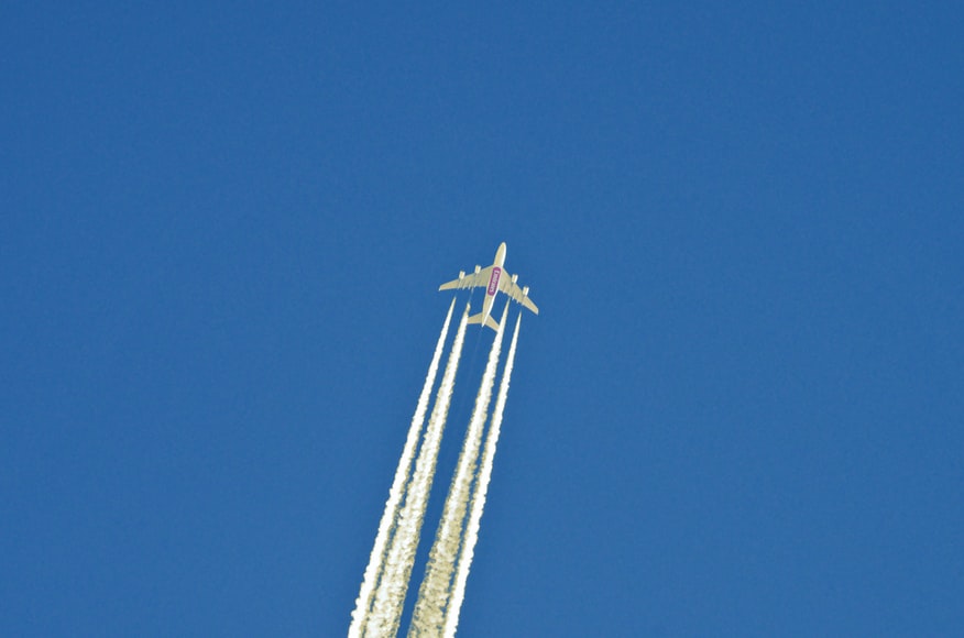 An Emirates aircraft flying through a clear sky with a trail behind, without the possibility of turbulence.