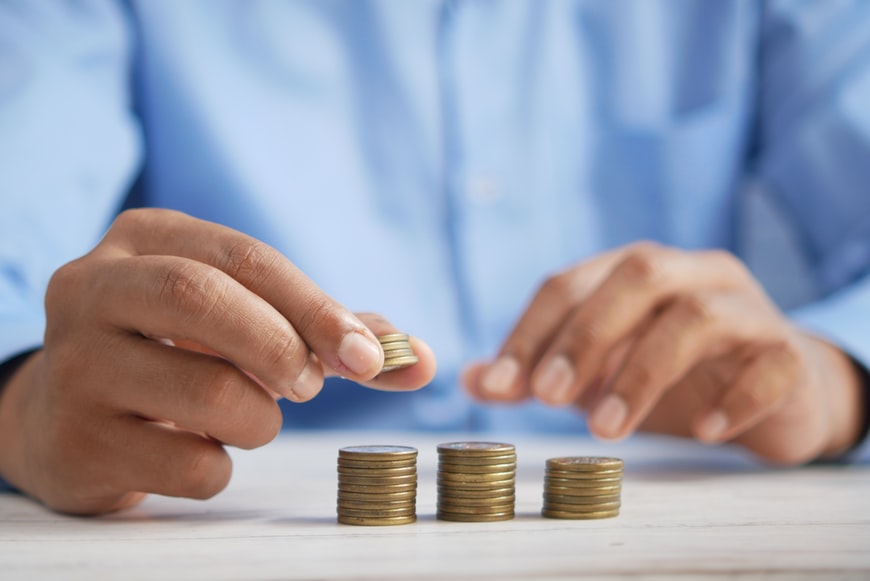 A visualisation of a man calculating his revenue in coins on a desk. 