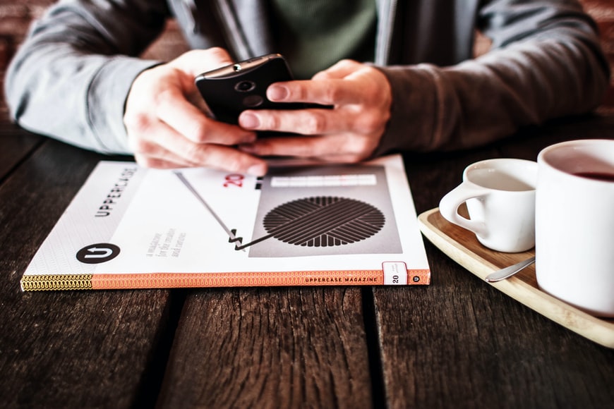 A businessman sitting at a desk with a course book and coffee, using a mobile learning app. 