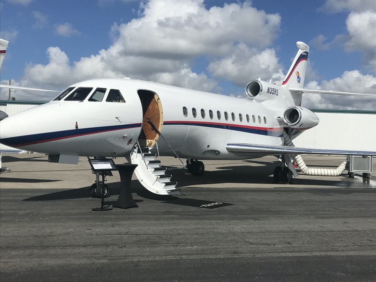 A private jet Falcon 900 stationed on a taxiway at an airport, ready for boarding.