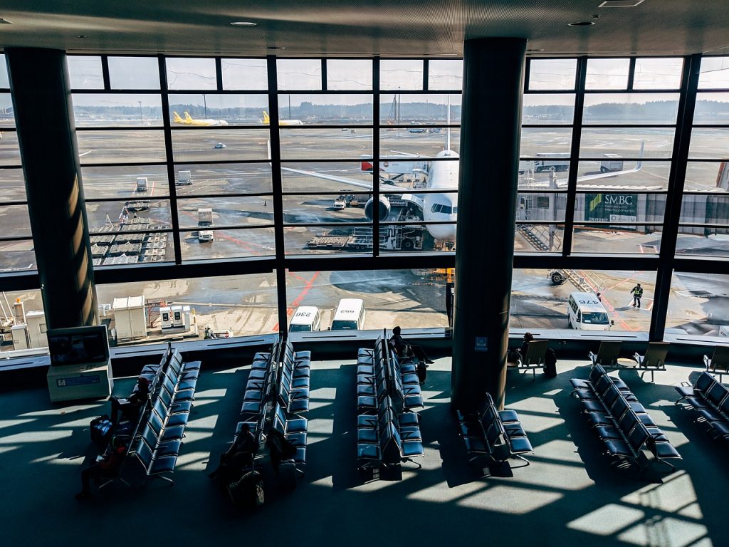 A central view of an airport terminal with a waiting hall and an aircraft parked at a jetway.