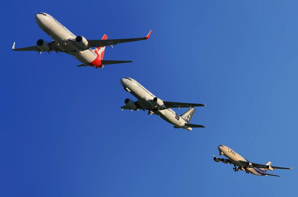 Three different aircraft are taking off in a blue sky.