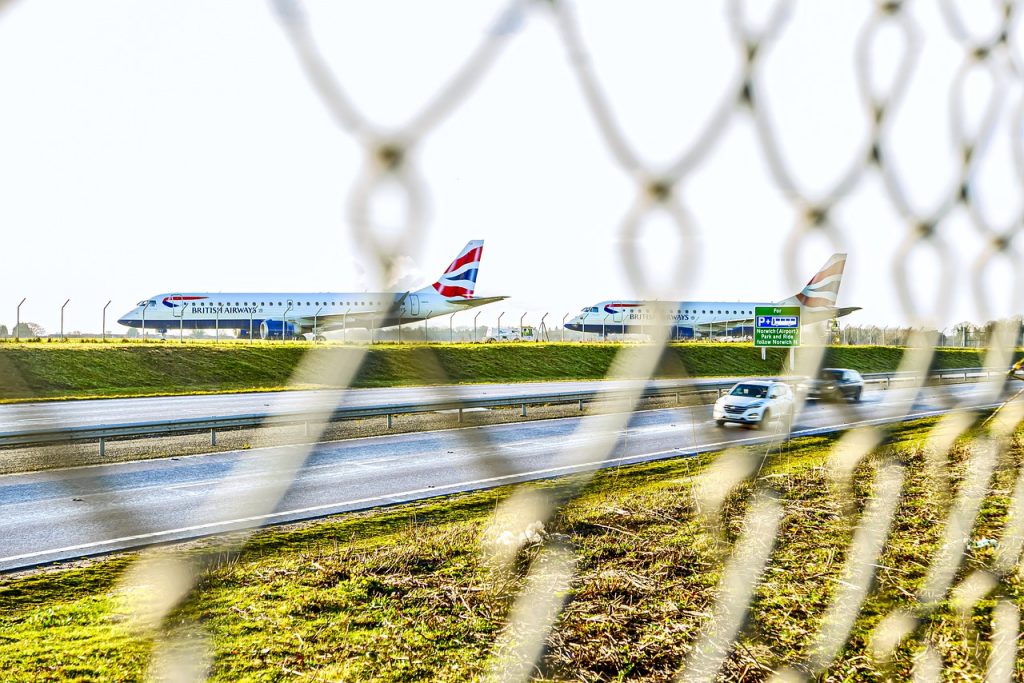 Leased aircraft parked behind a fence in airport territory.