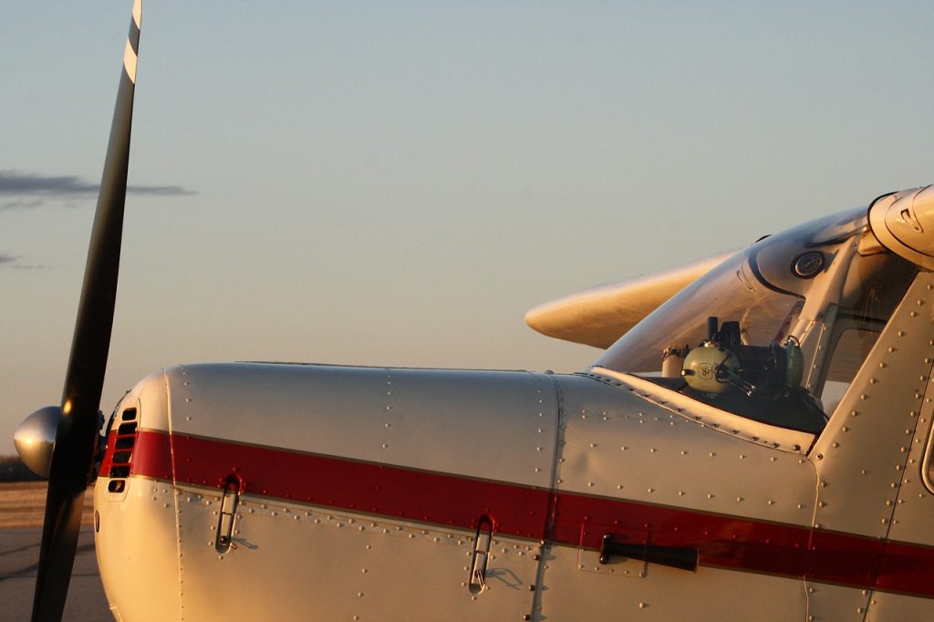 A central view of the nose and propeller of a small airplane during sunset. 