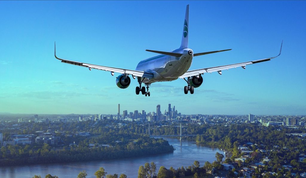 Airplane flying over a large city with skyscrapers during the day.