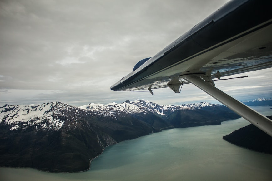 A small aircraft flying over a mountainous coast in Alaska. 