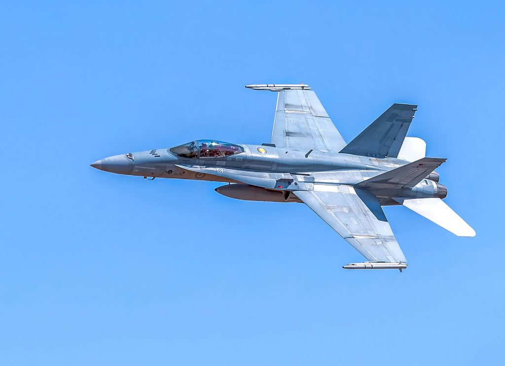 A fighter jet FA18A Hornet flying in a blue sky.