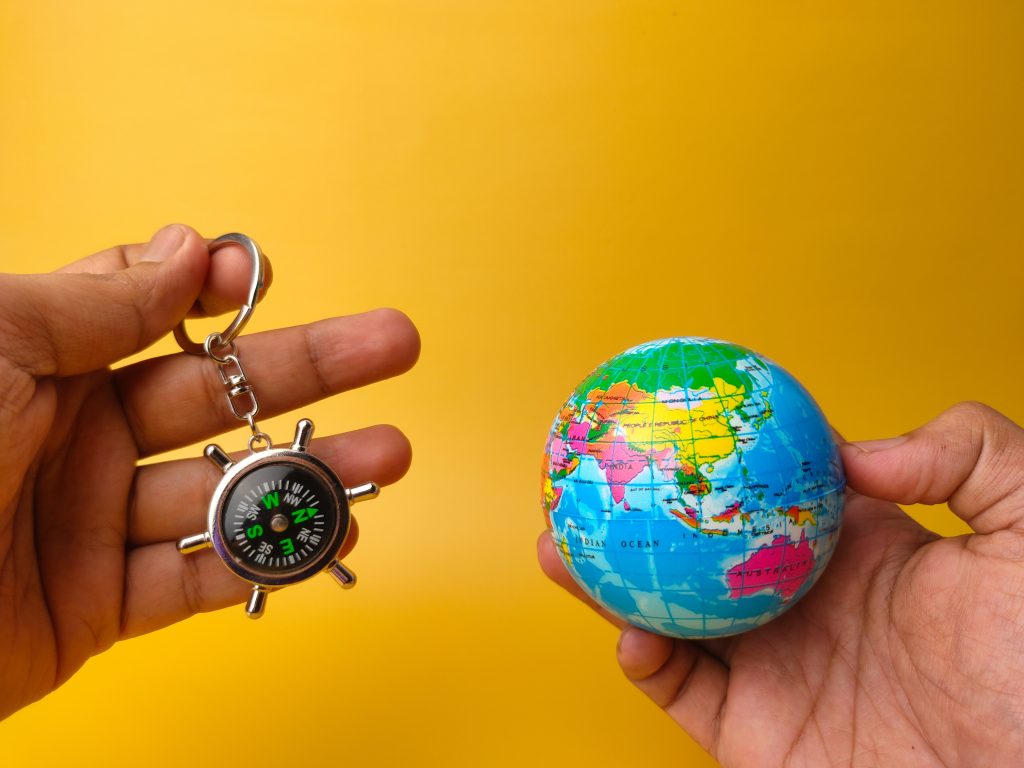 A visualization of navigating around the globe: a person holding a small compass and a small globe in their hands.