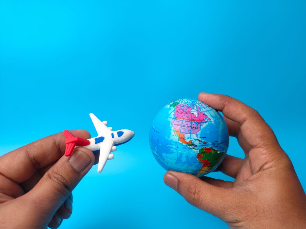 A visualization of a circumnavigation flight on a blue background: a person holding a plane model and a mini globe.